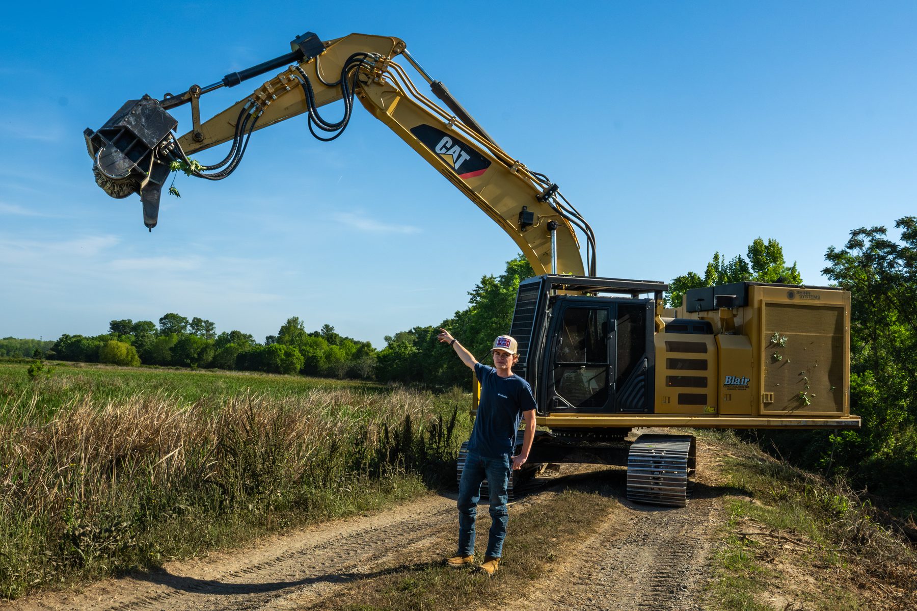 Operator standing in front of CAT excavator with forestry mulching head at Phinizy Swamp